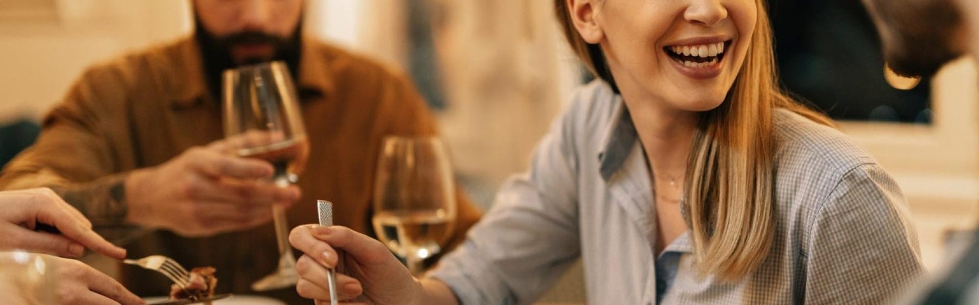 giovane-donna-felice-che-si-diverte-mentre-mangia-la-cena-e-comunica-con-gli-amici-al-tavolo-da-pranzo