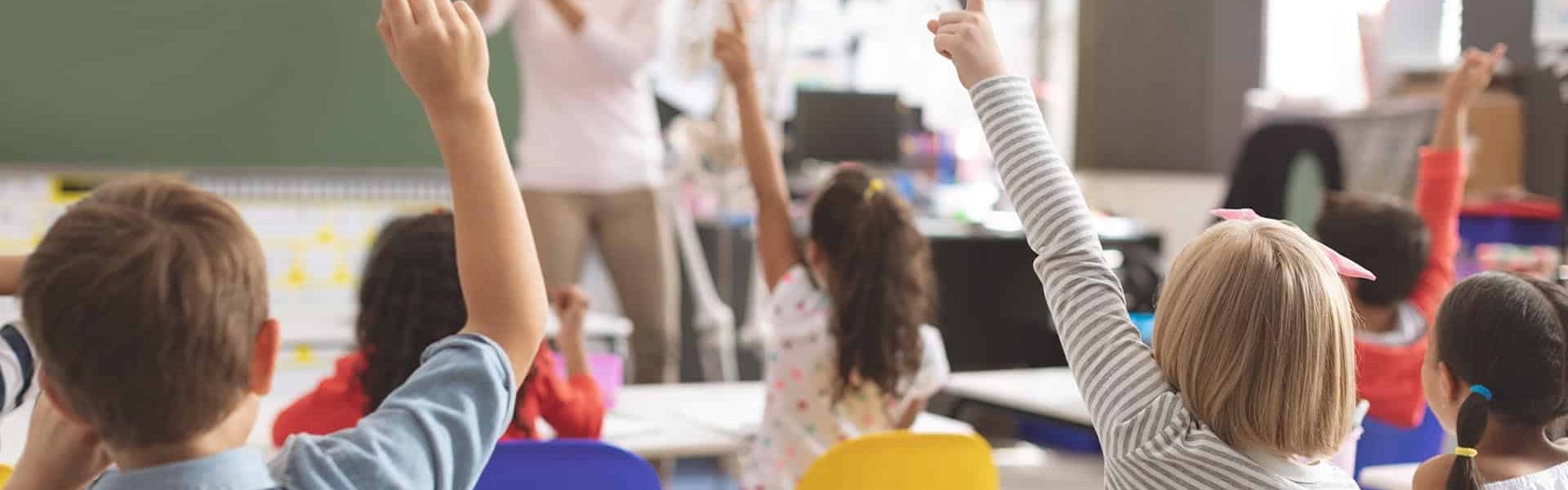 School kids raising hands while teacher explaining the functioni