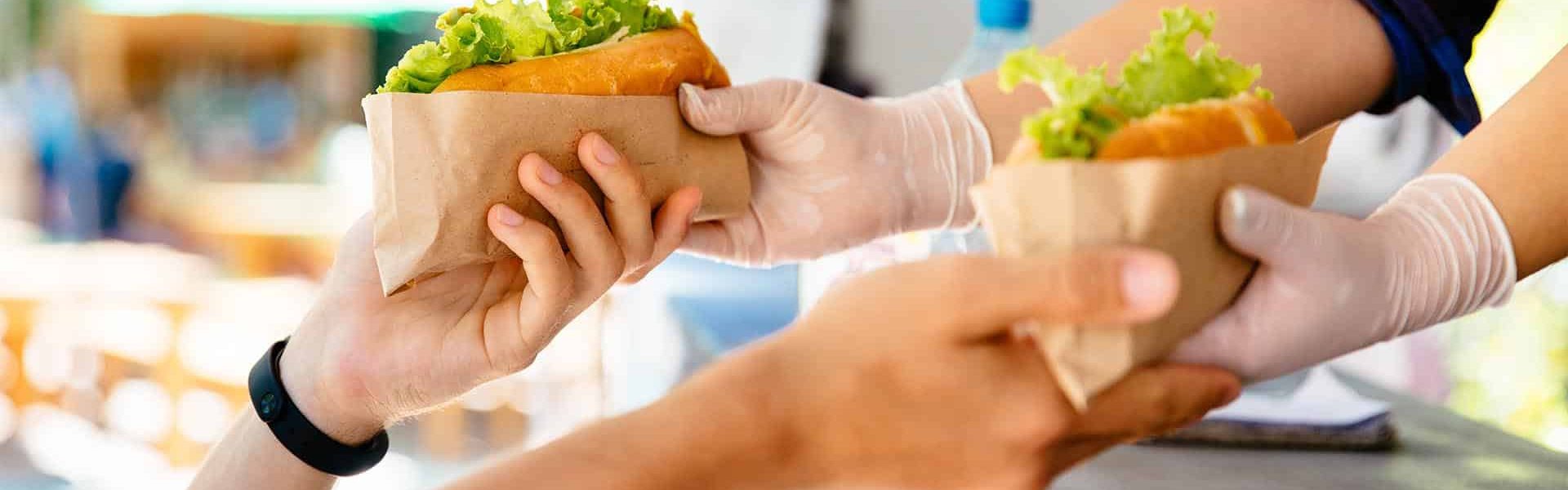 Man buying two hot dog in a kiosk, outdoors. Street food. Close-up view.